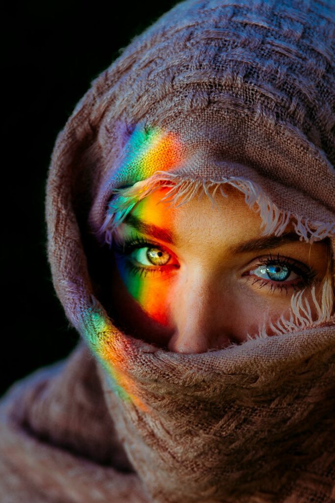 Rainbow light falling across a woman's eyes — colours coming alive on her face