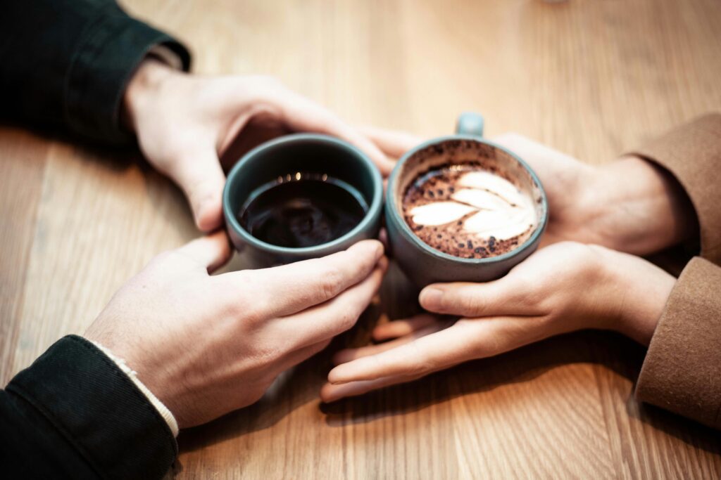 Two hands holding two cups of coffee and hot chocolate together — an emotional love story about a reunion the universe quietly arranged